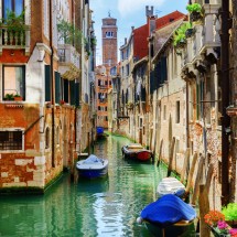 The Rio di San Cassiano Canal with boats and colorful facades of old medieval houses in Venice, Italy. Bell-tower of San Cassiano (Church of Saint Cassian) is visible in background.