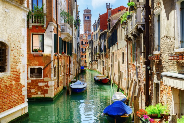 The Rio di San Cassiano Canal with boats and colorful facades of old medieval houses in Venice, Italy. Bell-tower of San Cassiano (Church of Saint Cassian) is visible in background.